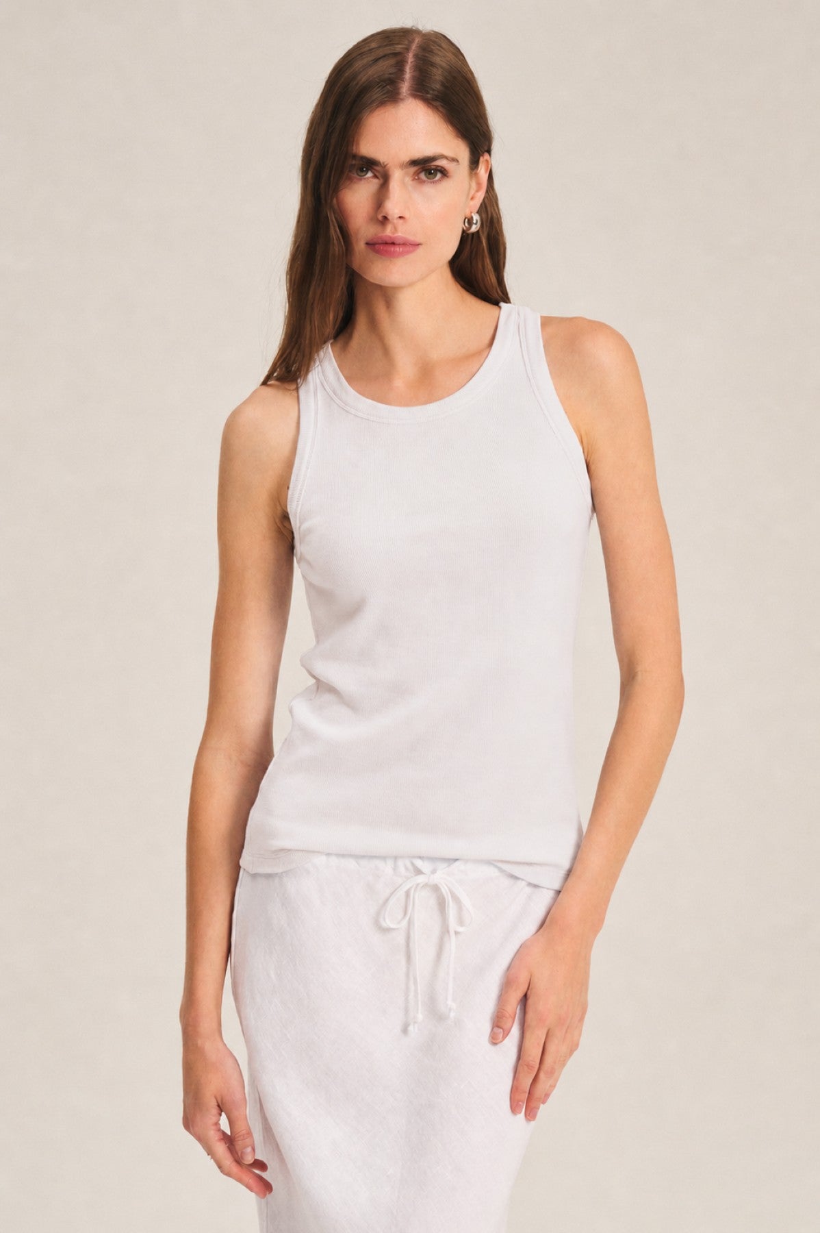 A woman stands against a neutral background, wearing the CRUZ TANK TOP by Velvet by Jenny Graham and a drawstring white skirt—timeless essentials for any capsule wardrobe.