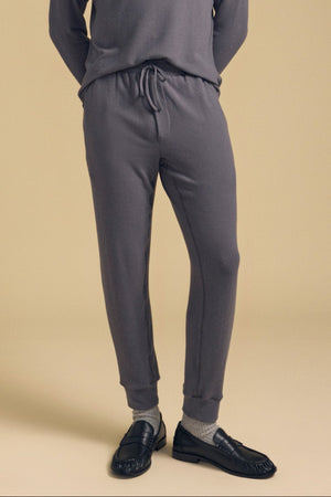 A person wears the ELLIS SWEATPANT by Velvet by Graham & Spencer, paired with a matching top, gray socks, and black loafers, standing against a plain beige background.