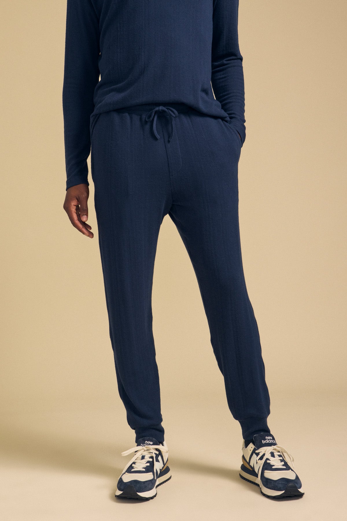 A person wearing navy blue cotton jersey ELLIS SWEATPANTs by Velvet by Graham & Spencer with a drawstring waist and navy and white athletic shoes.-46288258498753