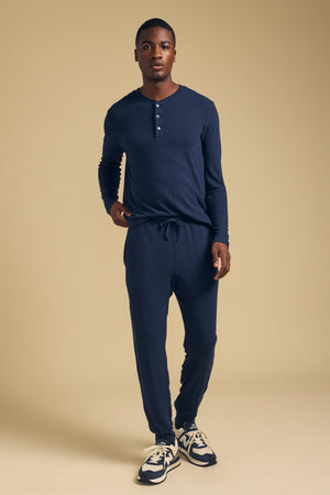 A man wearing a navy long-sleeve henley shirt and matching navy ELLIS SWEATPANT lounge pants with a drawstring waist.