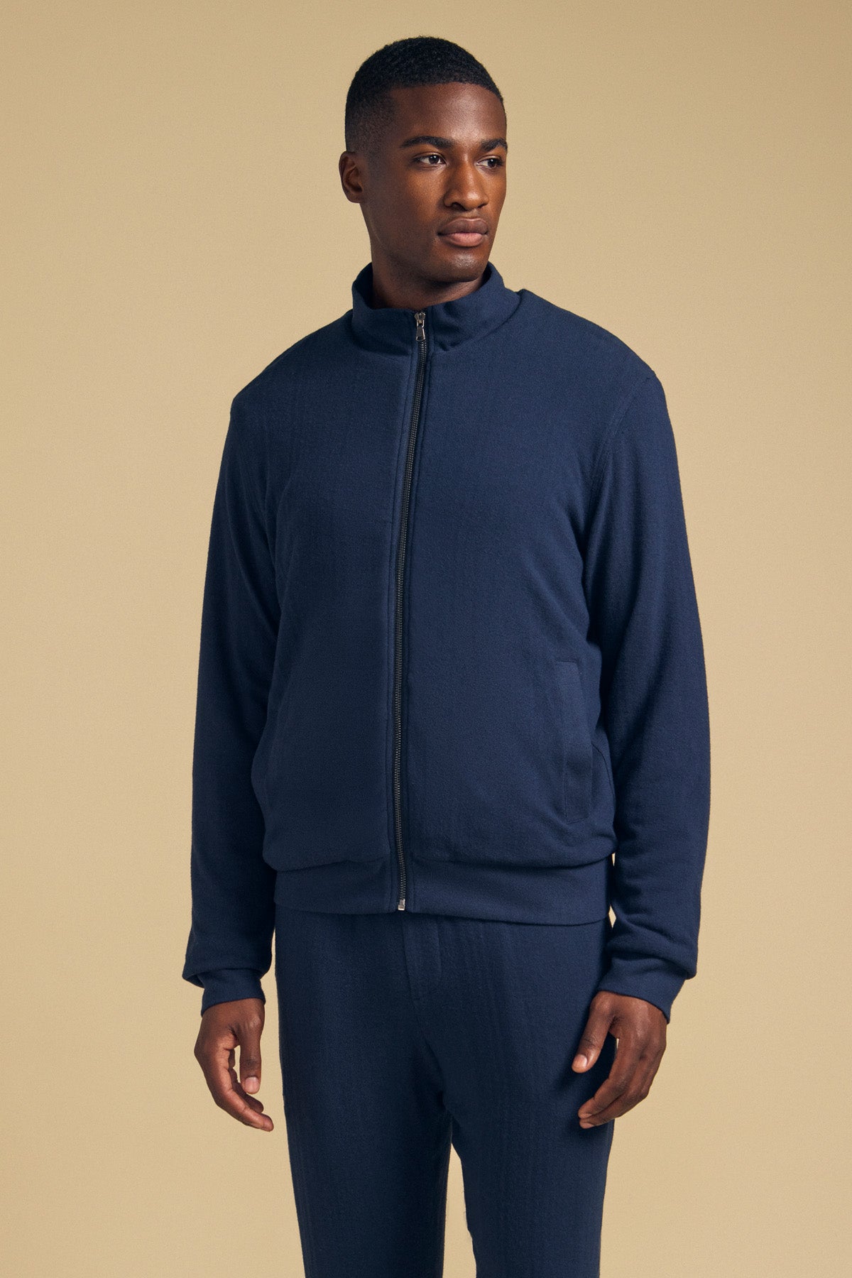 A man wearing a navy blue Velvet by Graham & Spencer NASH JACKET with a full-zip closure and a mock neck.