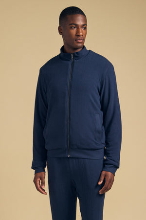 A man wearing a navy blue Velvet by Graham & Spencer NASH JACKET with a full-zip closure and a mock neck.