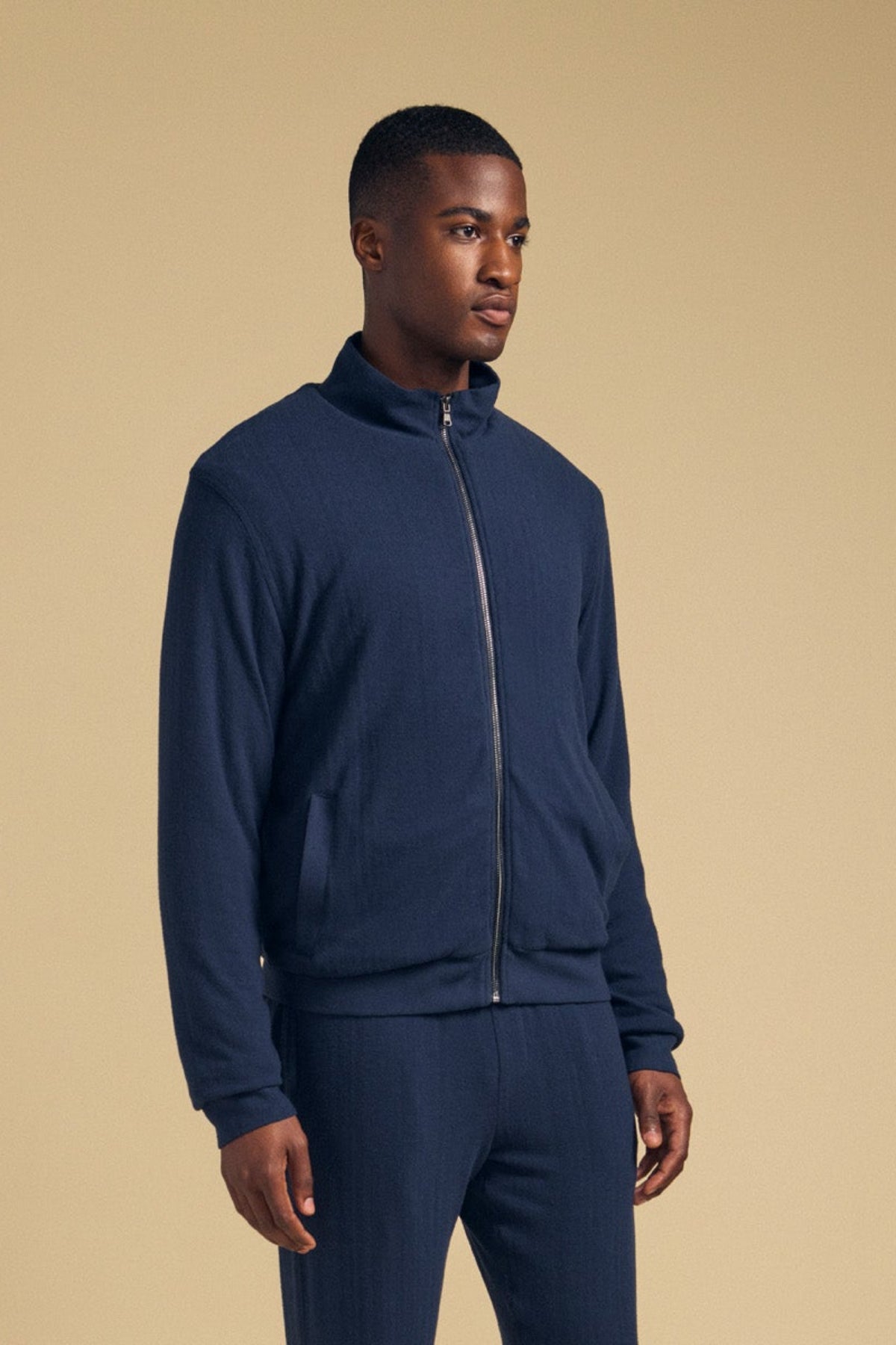 A man wearing a cozy NASH JACKET full-zip jersey and matching joggers with neutral-toned sneakers.