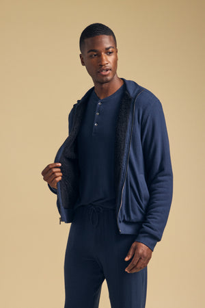 A man wearing a cozy NASH JACKET full-zip hoodie with a dark textured lining over a matching henley shirt and lounge pants.