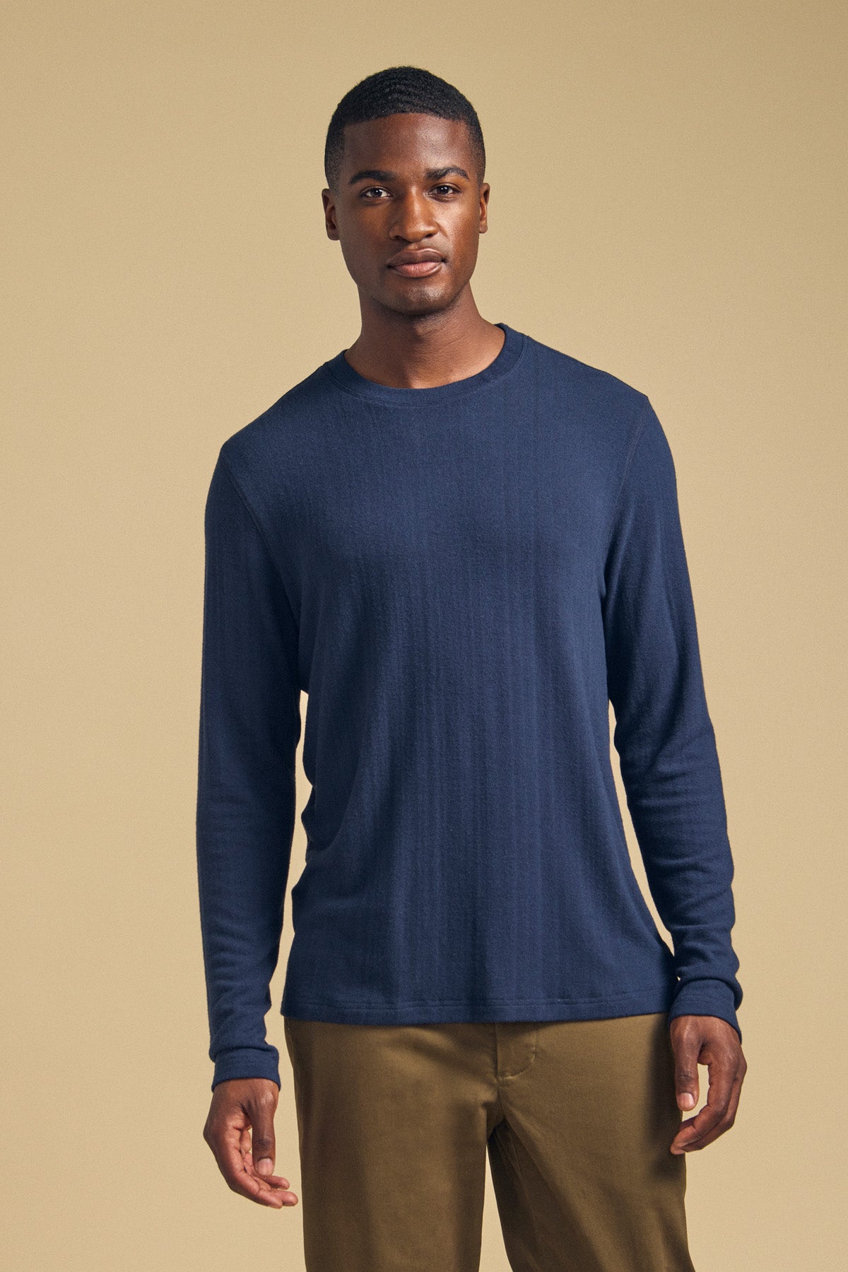 A man wears a cozy, navy blue Velvet by Graham & Spencer REDDEN CREW PULLOVER with brown pants.-46288509993153
