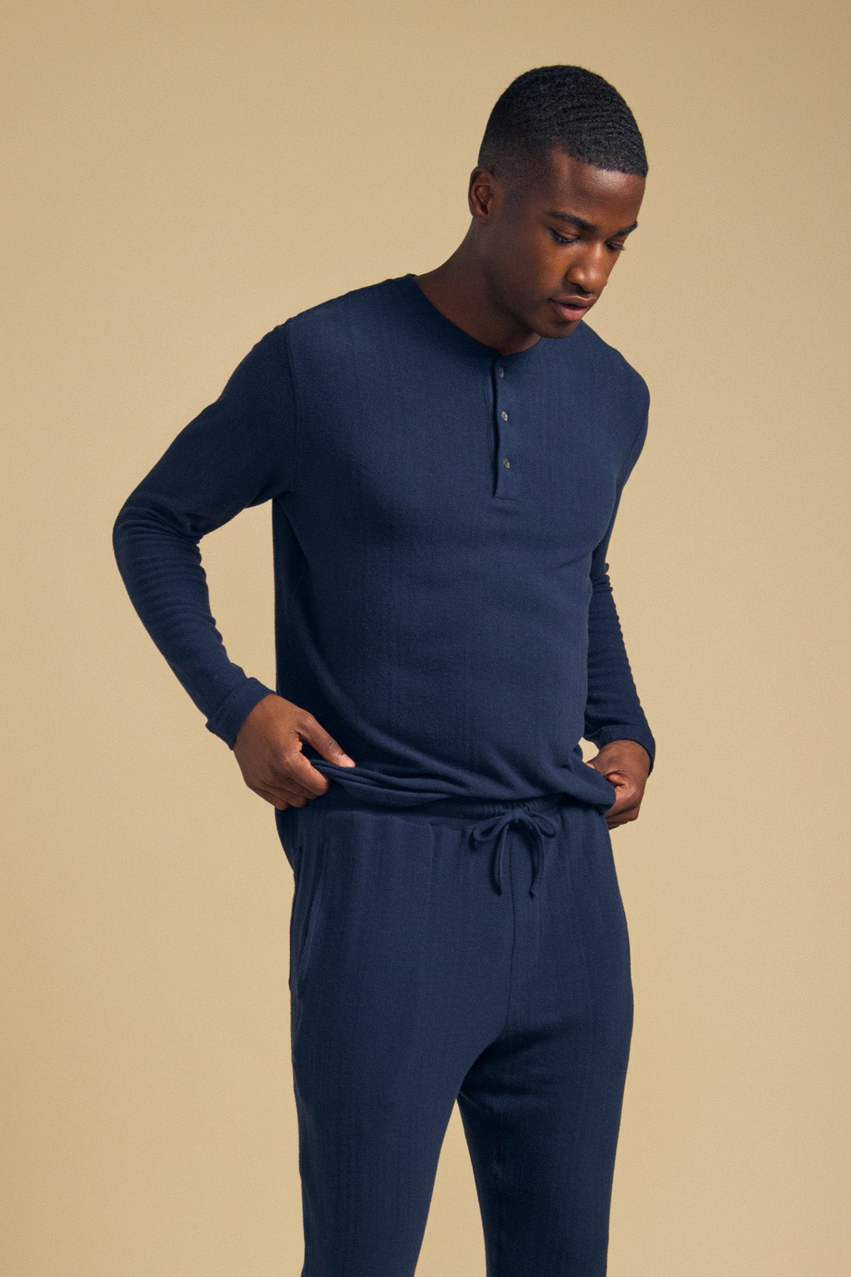 A man wearing a navy blue TYLER HENLEY long-sleeved jersey shirt and matching drawstring pants.