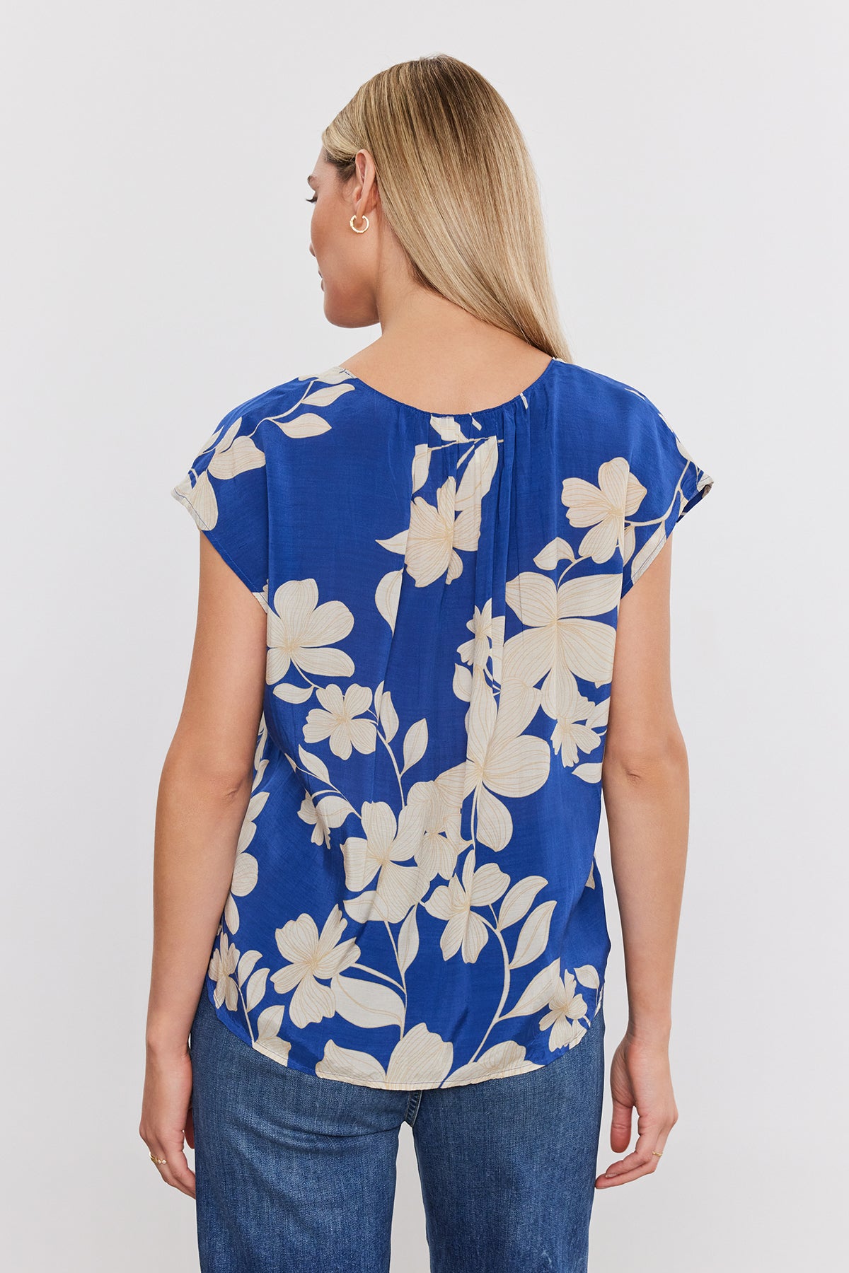 The woman is seen from the back, wearing a Velvet by Graham & Spencer SHAYLEN PRINTED SCOOP NECK top.-35655290454209