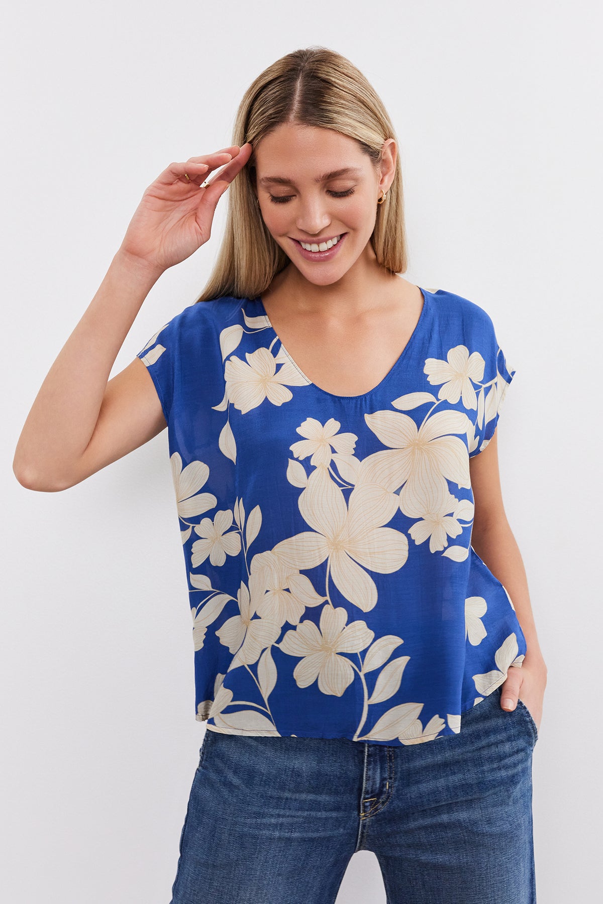 A woman wearing a blue SHAYLEN PRINTED SCOOP NECK top by Velvet by Graham & Spencer and jeans.-35655290486977