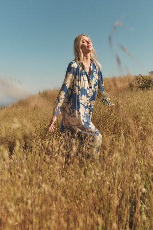 A woman in a JOSEPHA PRINTED DRESS by Velvet by Graham & Spencer standing in a field.