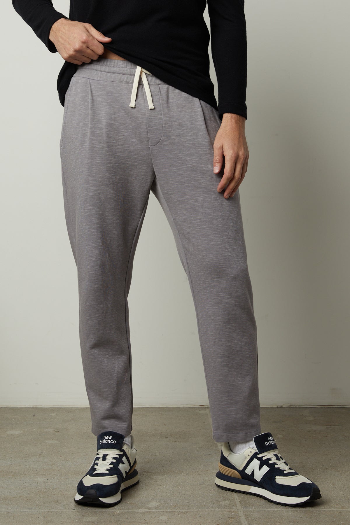 A man wearing Velvet by Graham & Spencer grey Parker sweatpants and a black t - shirt.-26846221271233