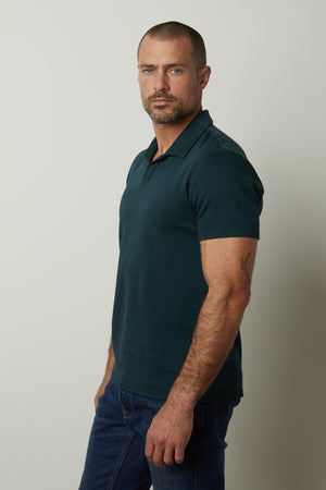 A man wearing jeans and a Velvet by Graham & Spencer DILAN COTTON BLEND POLO shirt.