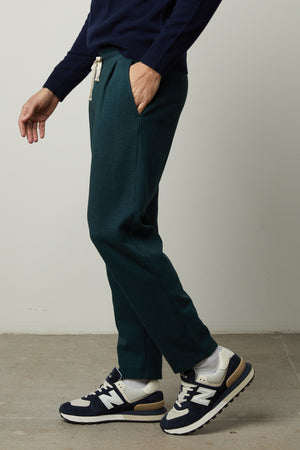 A man wearing a sweater and Velvet by Graham & Spencer PARKER SWEATPANT in dark green.