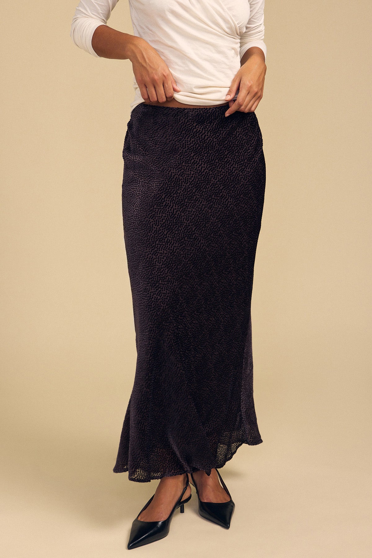 A person wears a dark, silk-viscose Velvet by Graham & Spencer QUINN DEVORE DOT SKIRT with a burnout texture and black pumps.