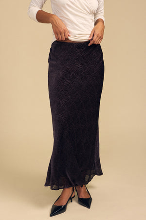 A person wears a dark, silk-viscose Velvet by Graham & Spencer QUINN DEVORE DOT SKIRT with a burnout texture and black pumps.