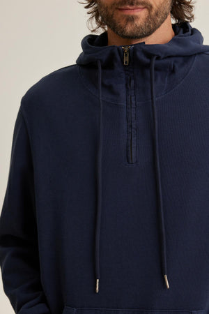 Someone wearing the MORTY HOODIE from Velvet by Graham & Spencer, featuring a dark blue color, hooded design, half-zip, and drawstrings.