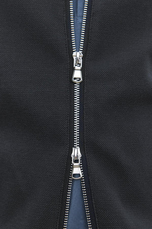 Close-up of the partially opened double zipper on the RYDELL JACKET by Velvet by Graham & Spencer, highlighting the metal teeth and two slider pull tabs against the black textured cotton blend fabric.