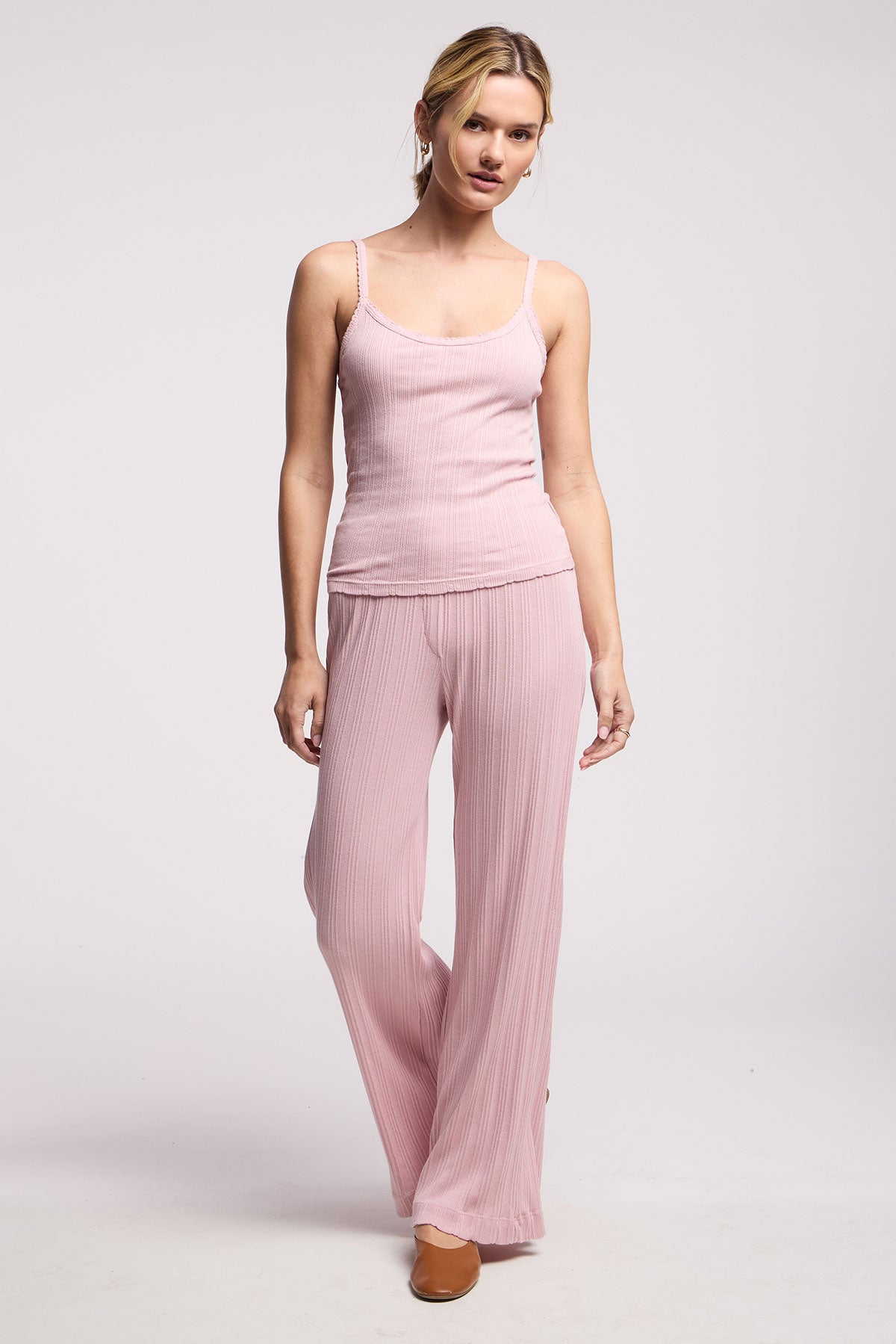 A woman wears the INIKU POINTELLE TANK TOP by Velvet by Graham & Spencer, a light pink ribbed cotton-modal tank, with matching wide-leg pants and brown flats, standing against a plain background.