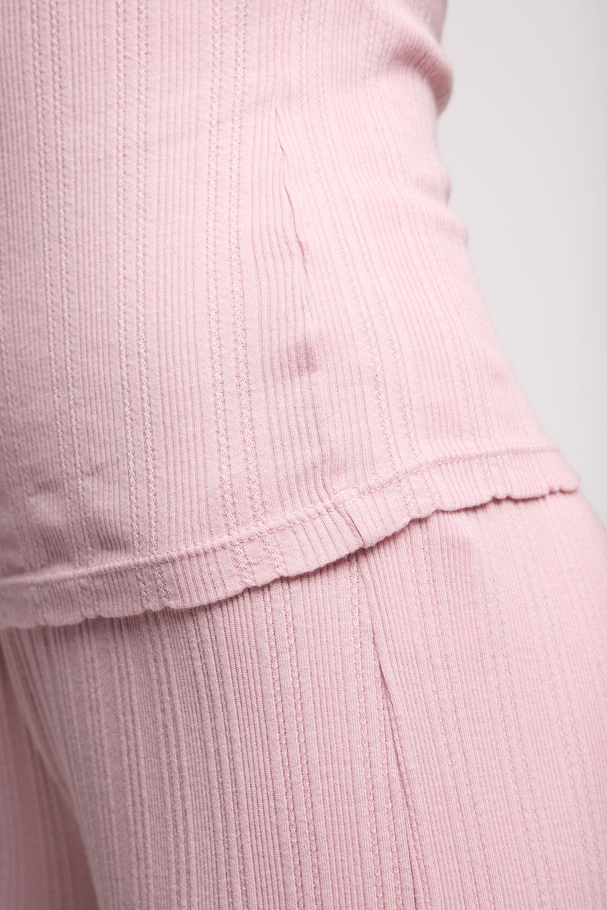 Close-up of a person wearing the INIKU POINTELLE TANK TOP by Velvet by Graham & Spencer, featuring a ribbed pink texture—ideal as a layering piece and showcasing the fabric’s detail.