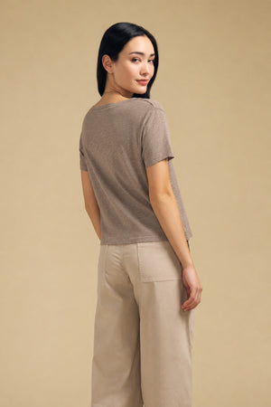 A woman wears a taupe short-sleeved cotton slub ELISHA TEE by Velvet by Graham & Spencer and beige trousers, a versatile wardrobe staple.
