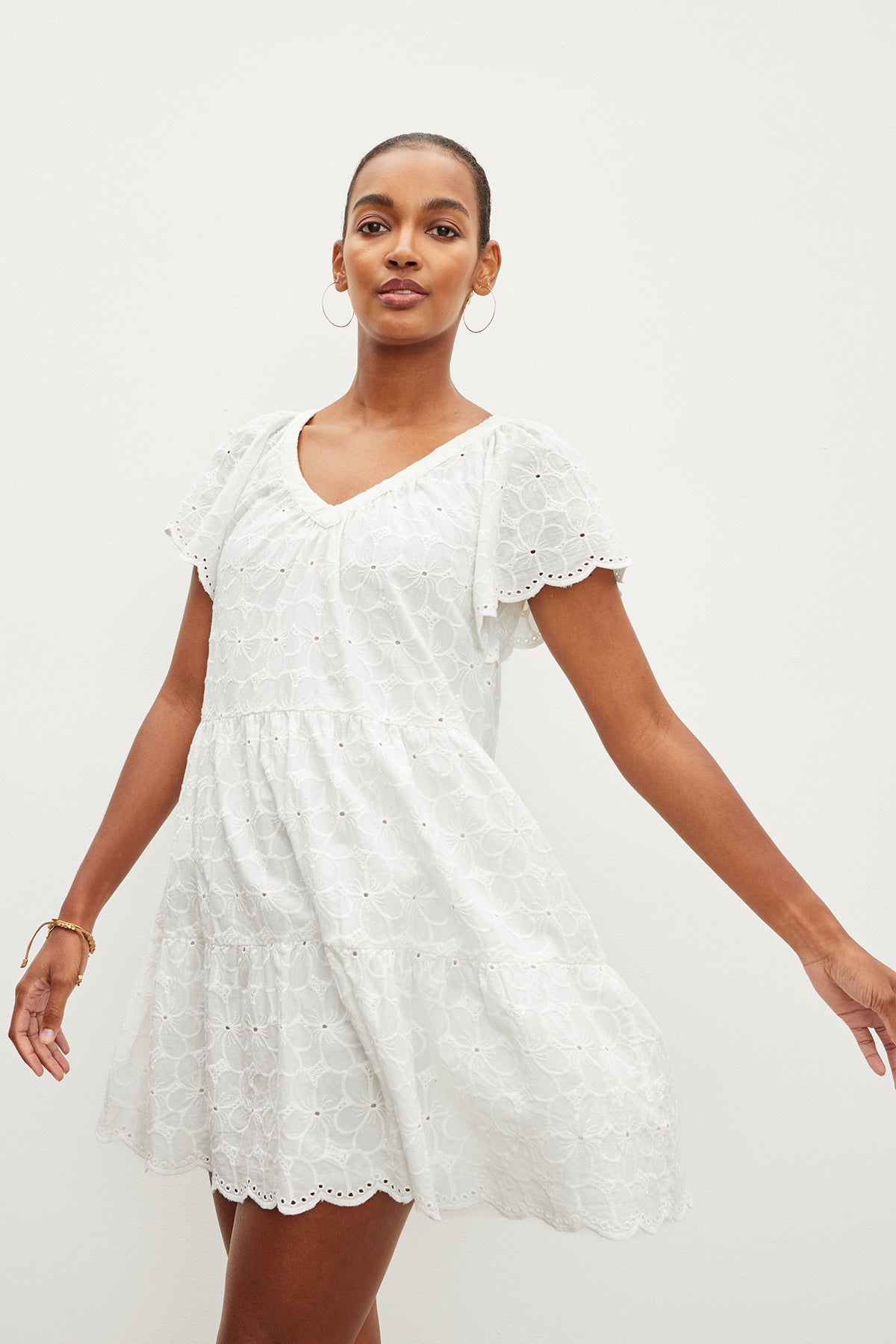   The model is wearing a white embroidered WYNETTE EMBROIDERED COTTON dress by Velvet by Graham & Spencer. 