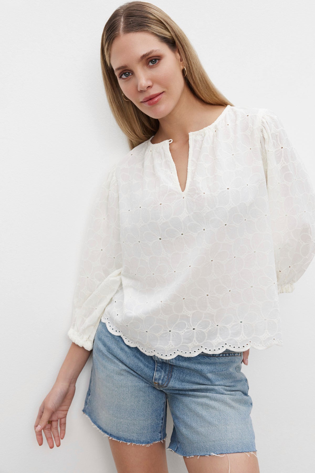   The model is wearing a CORINA EMBROIDERED COTTON TOP by Velvet by Graham & Spencer and denim shorts. 
