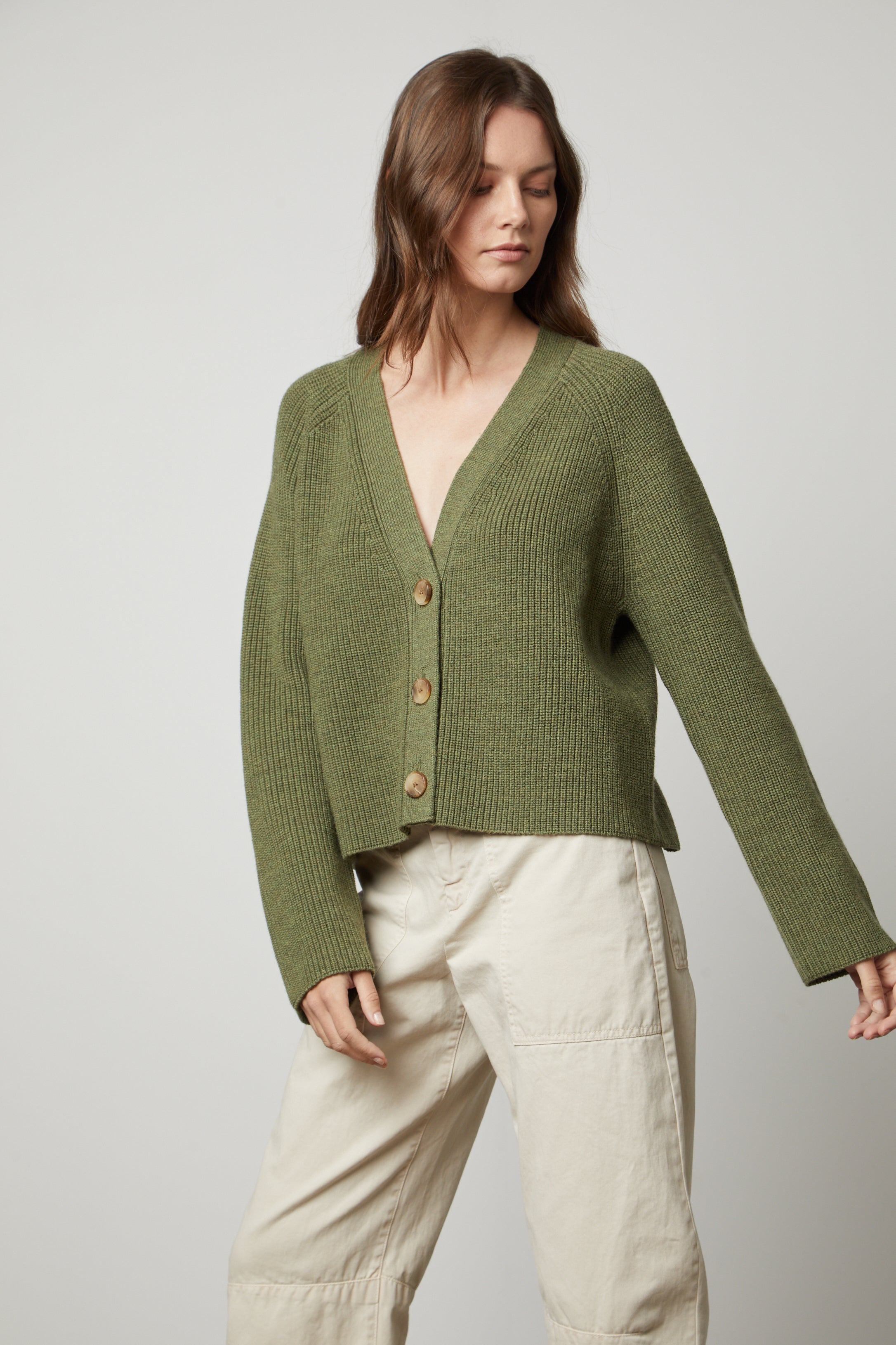   The model is wearing a green MARILYN BUTTON FRONT CARDIGAN made by Velvet by Graham & Spencer for warmth and comfort. 