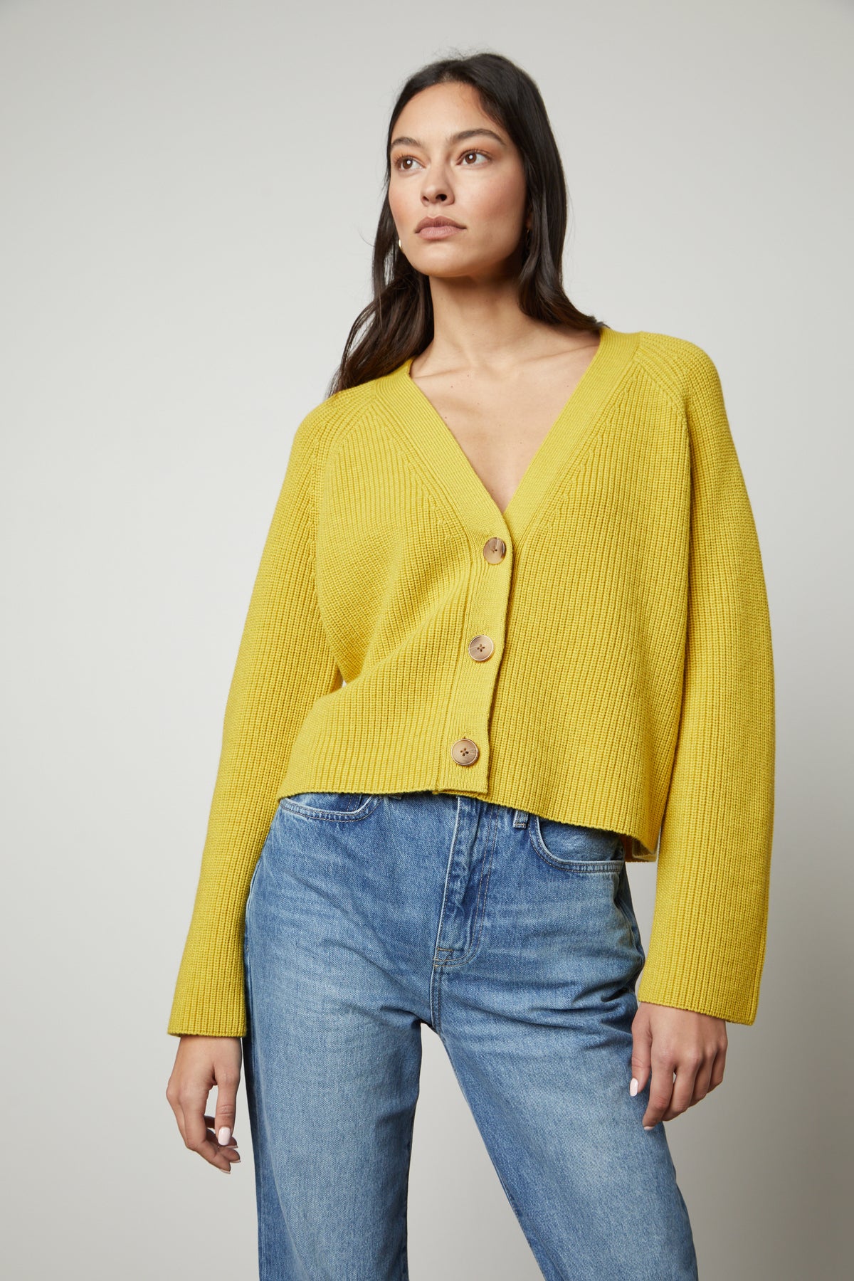   The model is wearing a yellow Marilyn Button Front Cardigan by Velvet by Graham & Spencer and jeans. 