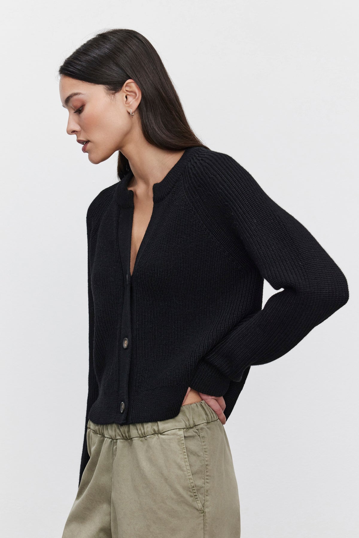 A woman modeling the SHAYLA CARDIGAN from Velvet by Graham & Spencer, a cozy black button-up, paired with khaki pants and her hands in her pockets, posed against a plain white background.-37856543703233