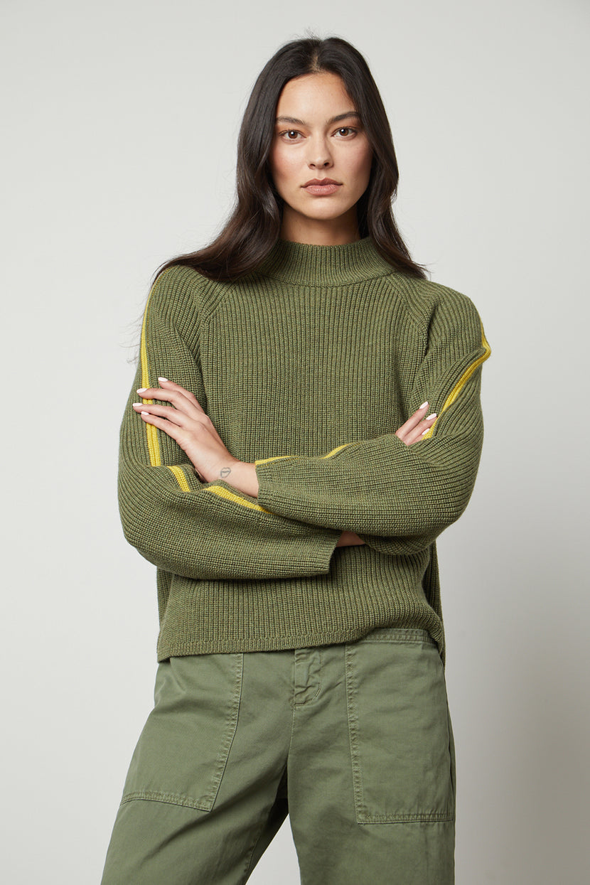 The model is wearing a comfortable Velvet by Graham & Spencer TEAGAN MOCK NECK SWEATER with yellow stripes.