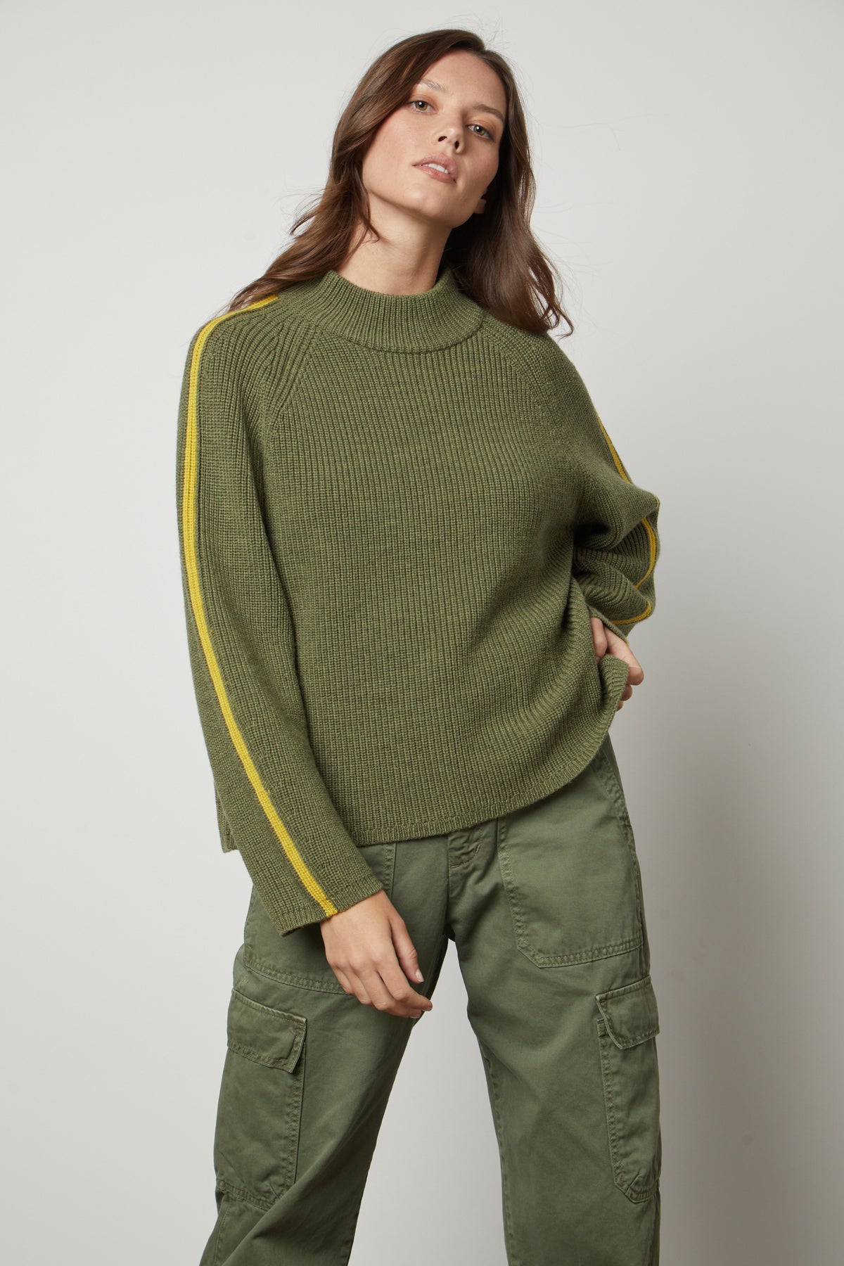   The model is wearing a TEAGAN MOCK NECK SWEATER by Velvet by Graham & Spencer and yellow cargo pants. 