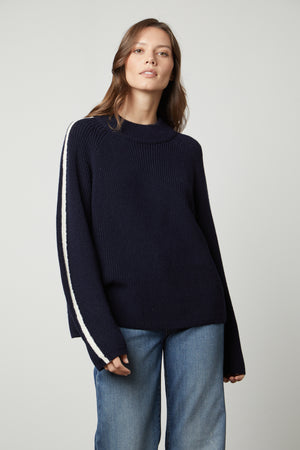 A model wearing a TEAGAN MOCK NECK SWEATER by Velvet by Graham & Spencer and jeans.