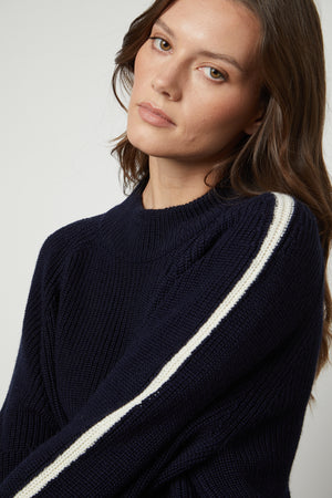 The model is wearing a cozy Velvet by Graham & Spencer TEAGAN MOCK NECK SWEATER.