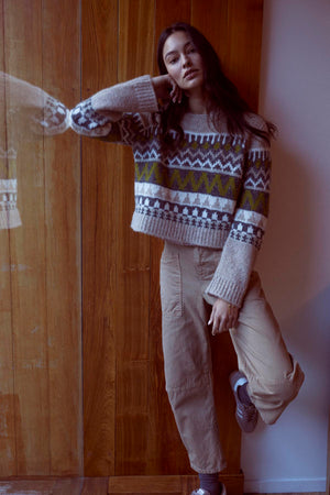 A woman in a casual sweater leaning against a wall, wearing Velvet by Graham & Spencer's BRYLIE SANDED TWILL UTILITY PANT.