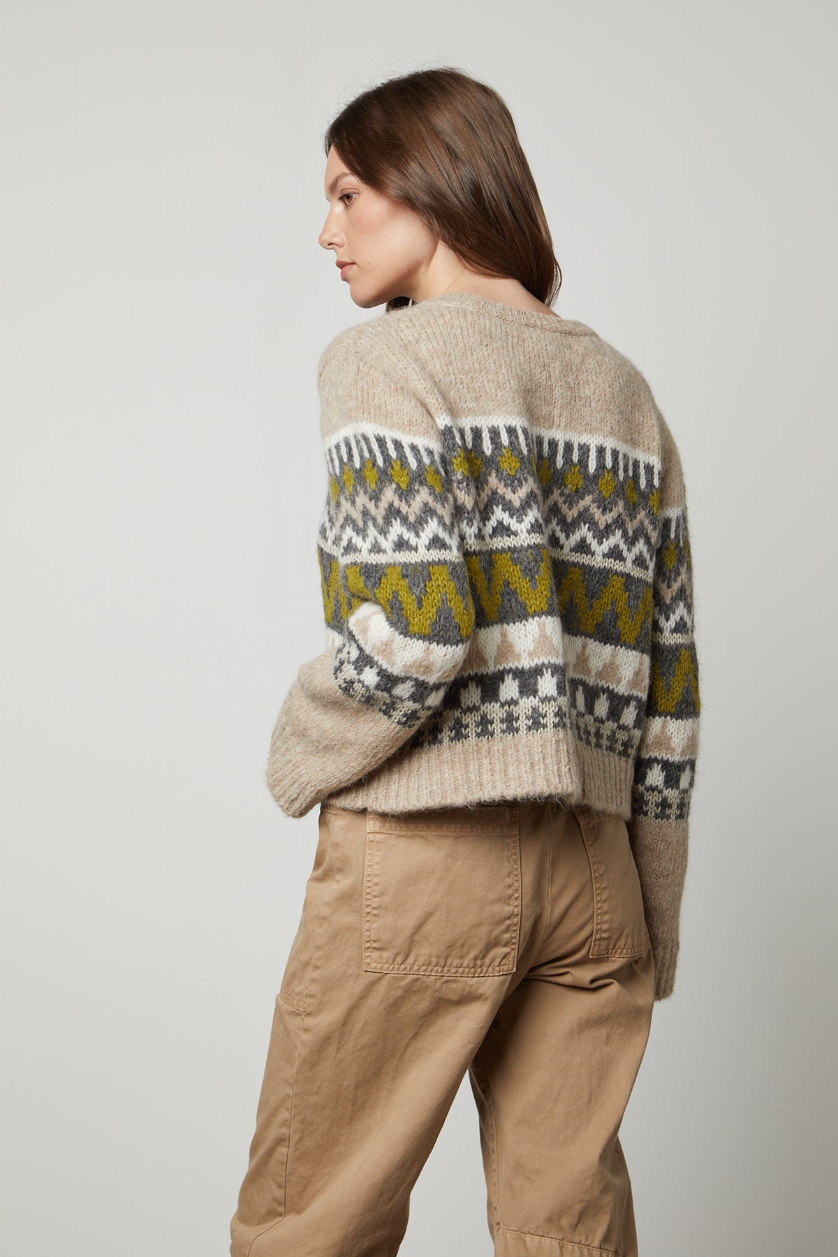 The back view of a woman wearing a cozy Velvet by Graham & Spencer MAKENZIE ALPACA CABLE KNIT CREW NECK SWEATER and khaki pants.-35626092986561