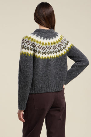 A person is shown from the back against a plain background, wearing the EDITH ALPACA SWEATER by Velvet by Graham & Spencer—a dark gray alpaca blend sweater featuring a yellow, white, and black patterned yoke—paired with dark pants.