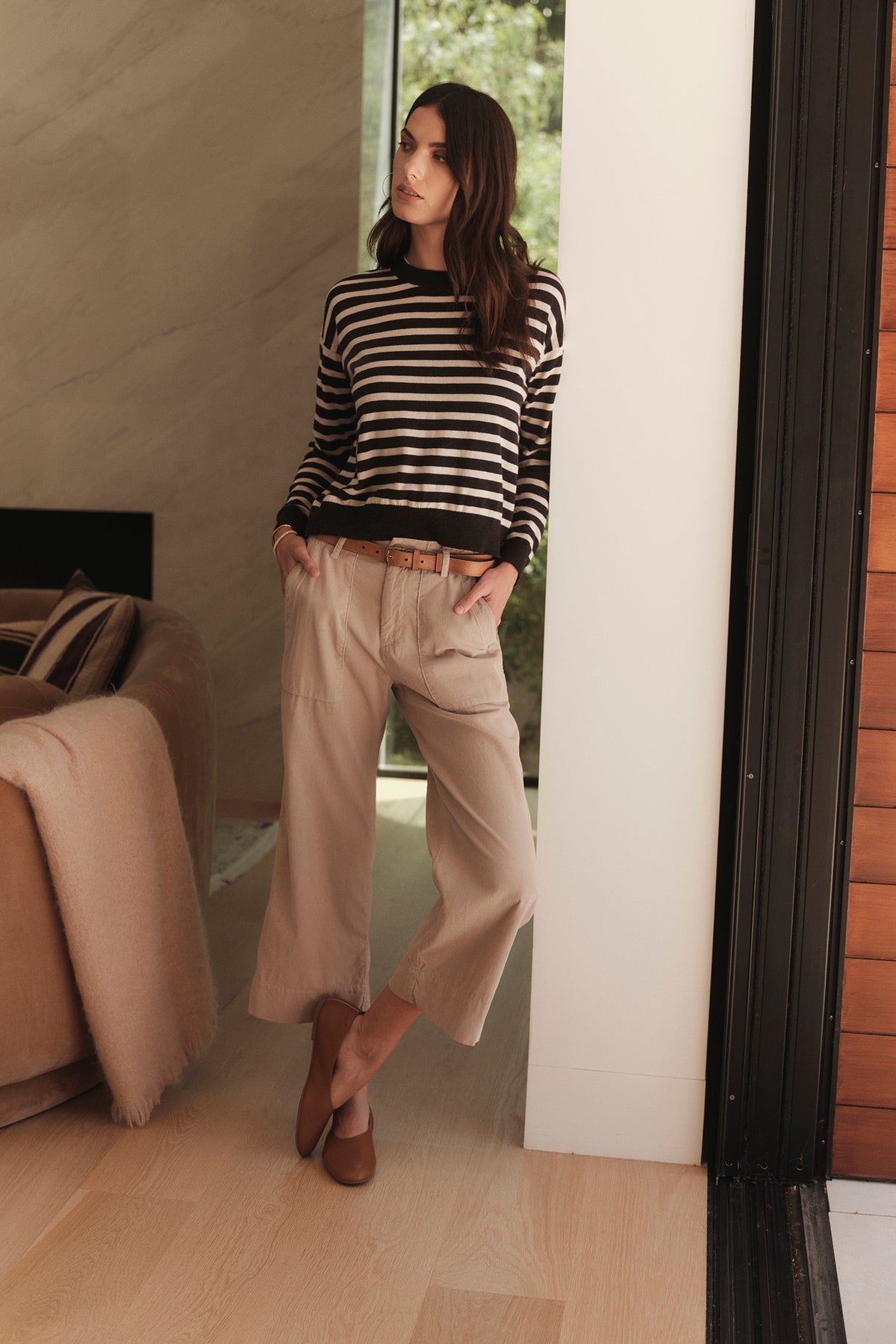   A woman wearing the Velvet by Graham & Spencer ALISTER STRIPED CREW NECK SWEATER and beige culottes. 