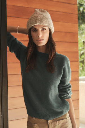 A woman wearing a tan sweater and a BYCHARI beanie.