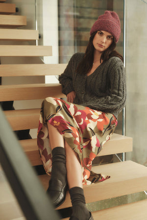 A woman is sitting on a staircase wearing a Velvet by Graham & Spencer KAIYA PRINTED SKIRT dress with an elastic waist.