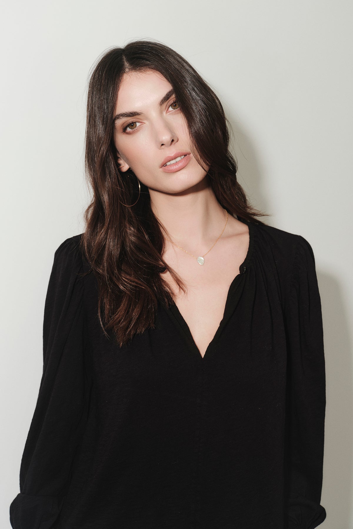 A woman in a black top, the IRINA SPLIT NECK TEE by Velvet by Graham & Spencer, posing for a photo.-26883564830913