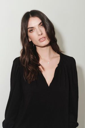 A woman in a black top, the IRINA SPLIT NECK TEE by Velvet by Graham & Spencer, posing for a photo.