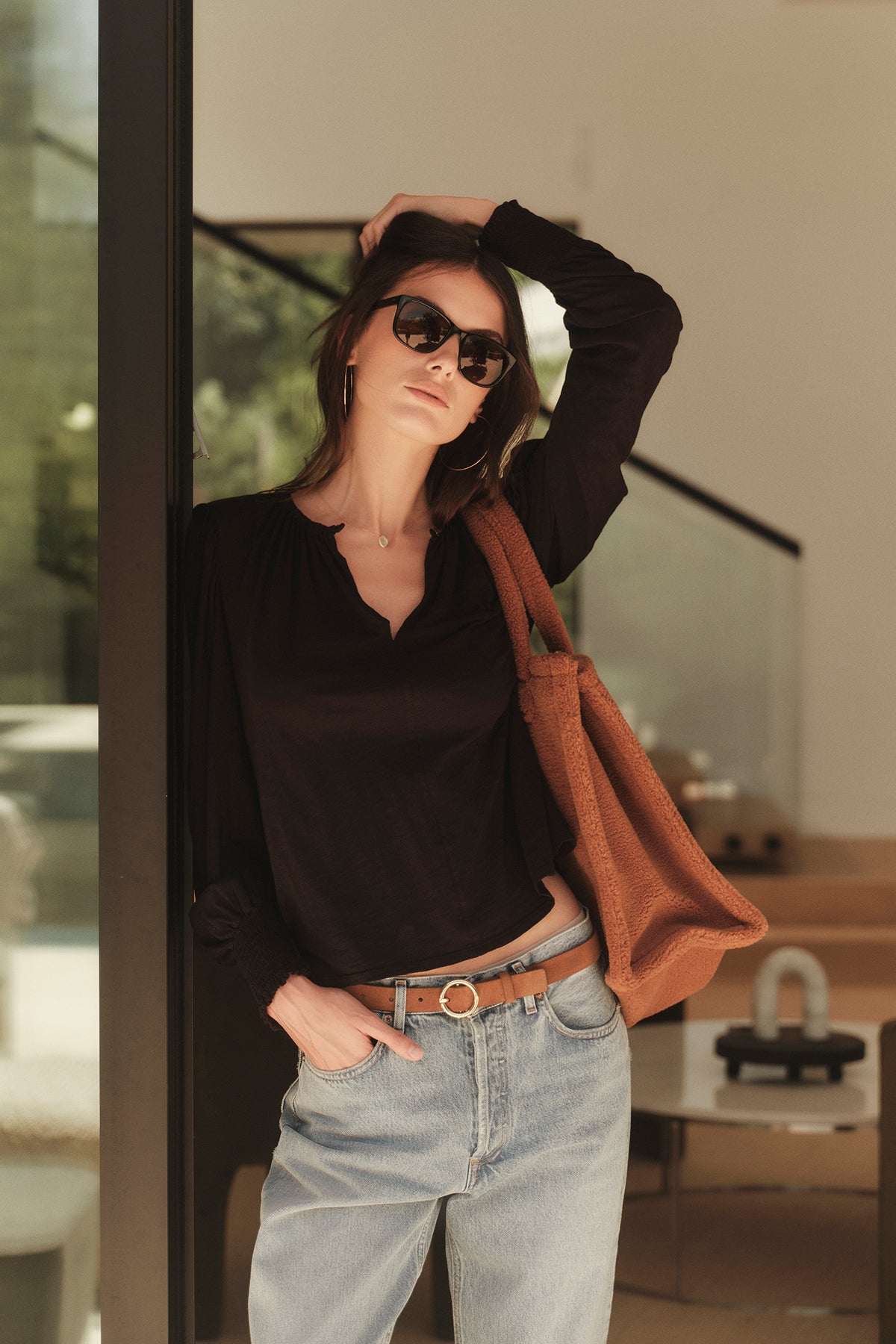 A woman wearing an IRINA SPLIT NECK TEE by Velvet by Graham & Spencer and jeans, and carrying a tan bag.-26883565813953