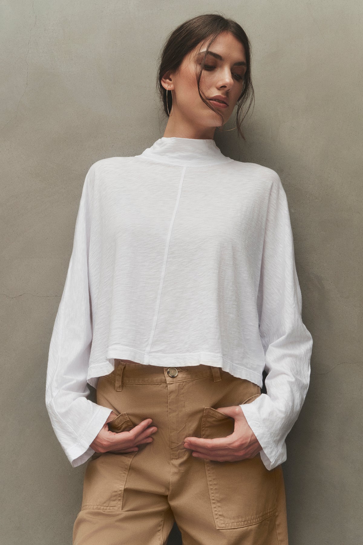 The model is wearing a white STACEY MOCK NECK TEE by Velvet by Graham & Spencer and tan pants.-26883549462721
