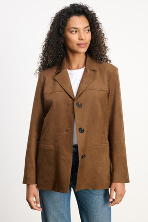 A woman models the SALIE FAUX SUEDE JACKET by Velvet by Graham & Spencer, styled with a white top and blue jeans against a plain light background.
