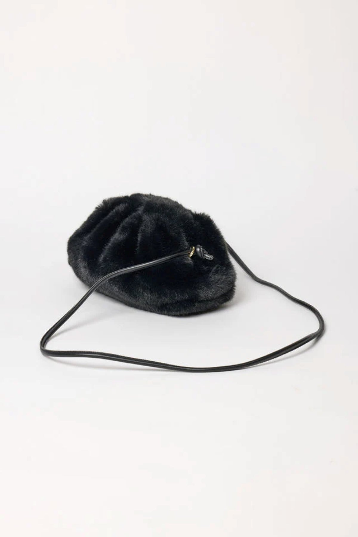 The FAUX FUR CLUTCH by Velvet by Graham & Spencer, a small black purse with a long thin strap, is displayed on a simple light background.
