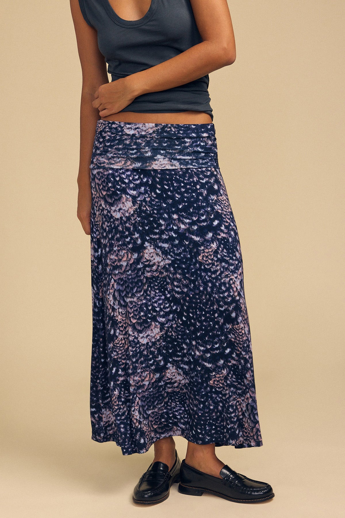 A person wearing a dark grey crop top and a VALERIE PRINTED SKIRT, paired with black loafers.-46489759580353