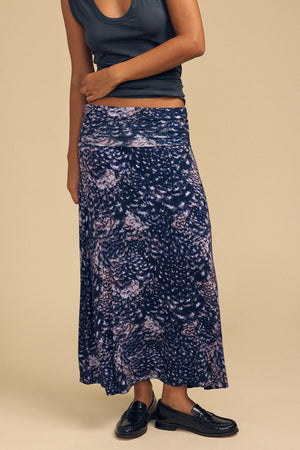 A person wearing a dark grey crop top and a VALERIE PRINTED SKIRT, paired with black loafers.