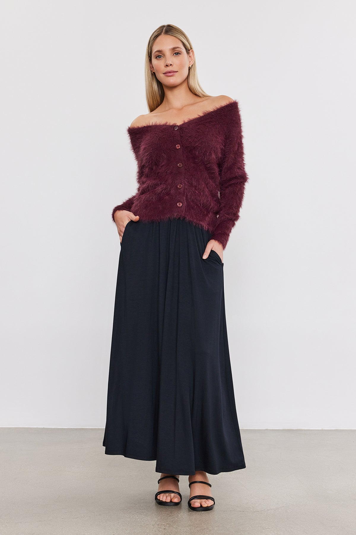 The model is wearing a burgundy sweater and black MALAYA MAXI SKIRT by Velvet by Graham & Spencer.-35660947882177