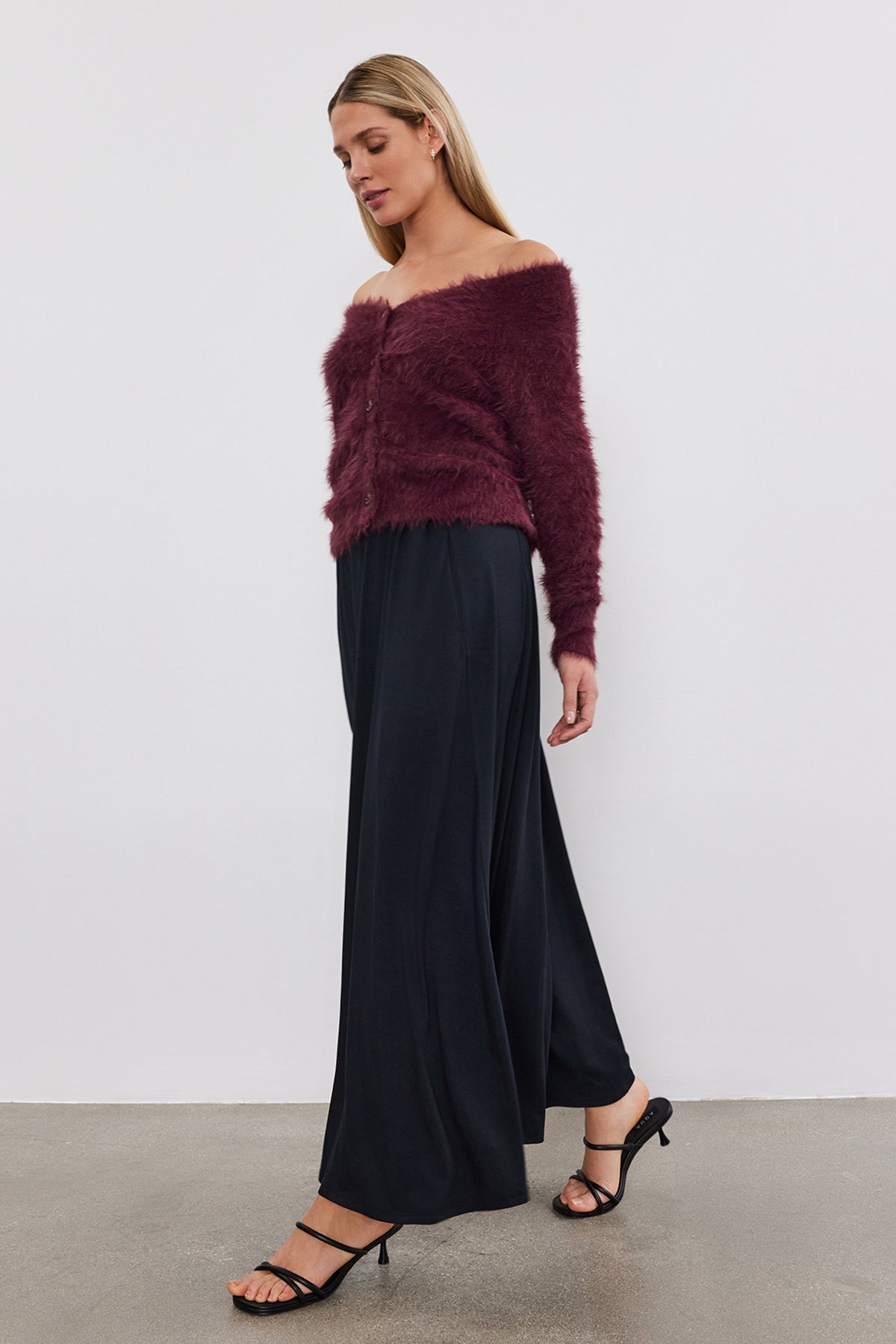   The model is wearing a burgundy MALAYA MAXI SKIRT by Velvet by Graham & Spencer and black wide leg pants made from soft jersey knit fabric. 