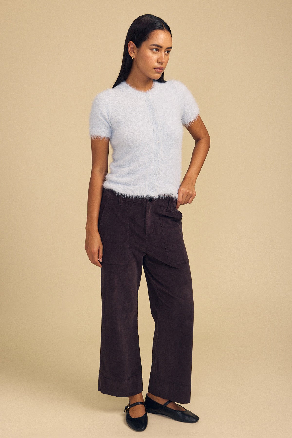 A person wears a soft, light blue GABBY FEATHER YARN CARDIGAN with dark brown wide-leg pants and black Mary Jane flats.-46489549930689