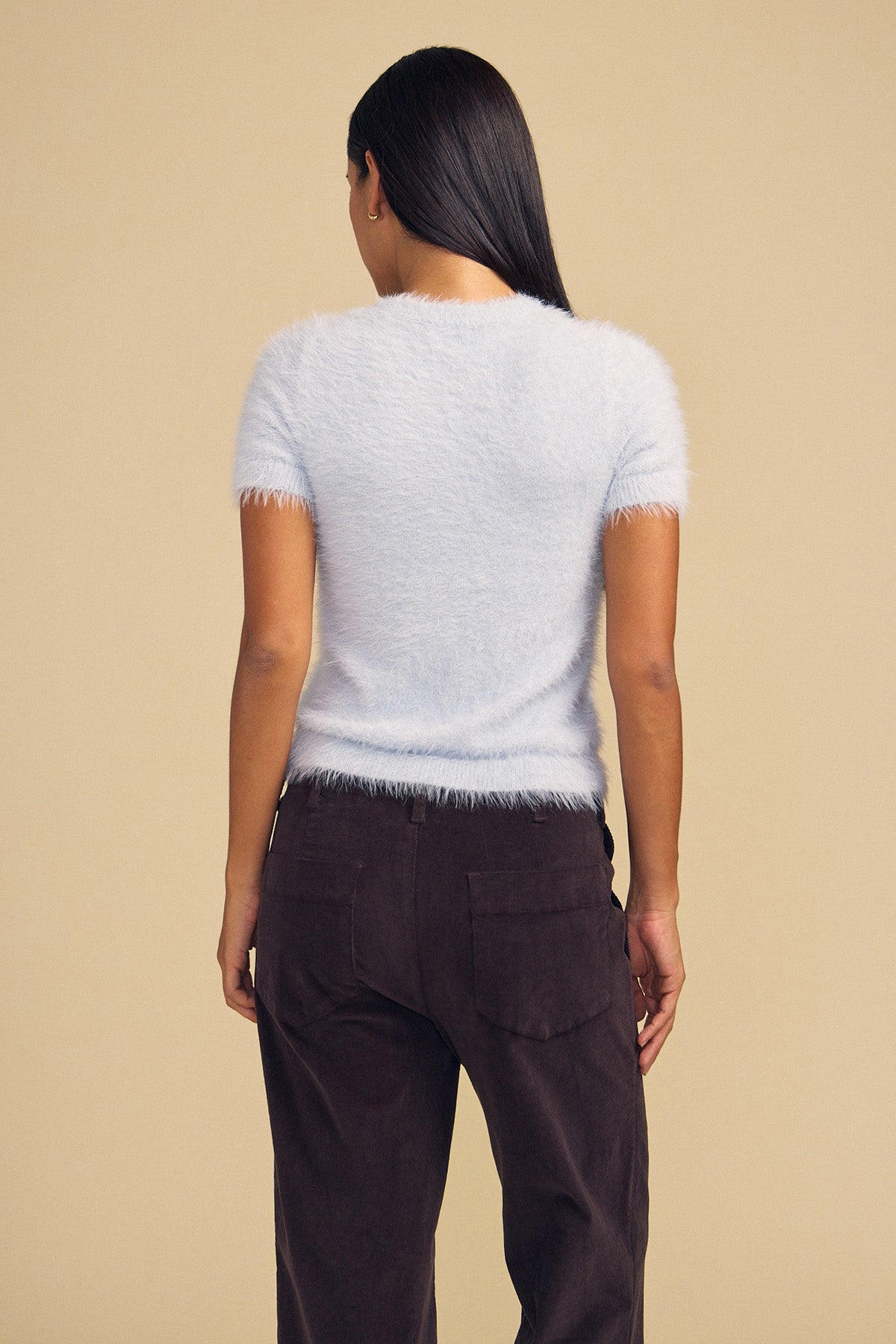 Back view of a person wearing a light blue GABBY FEATHER YARN CARDIGAN and dark pants.-46489549963457